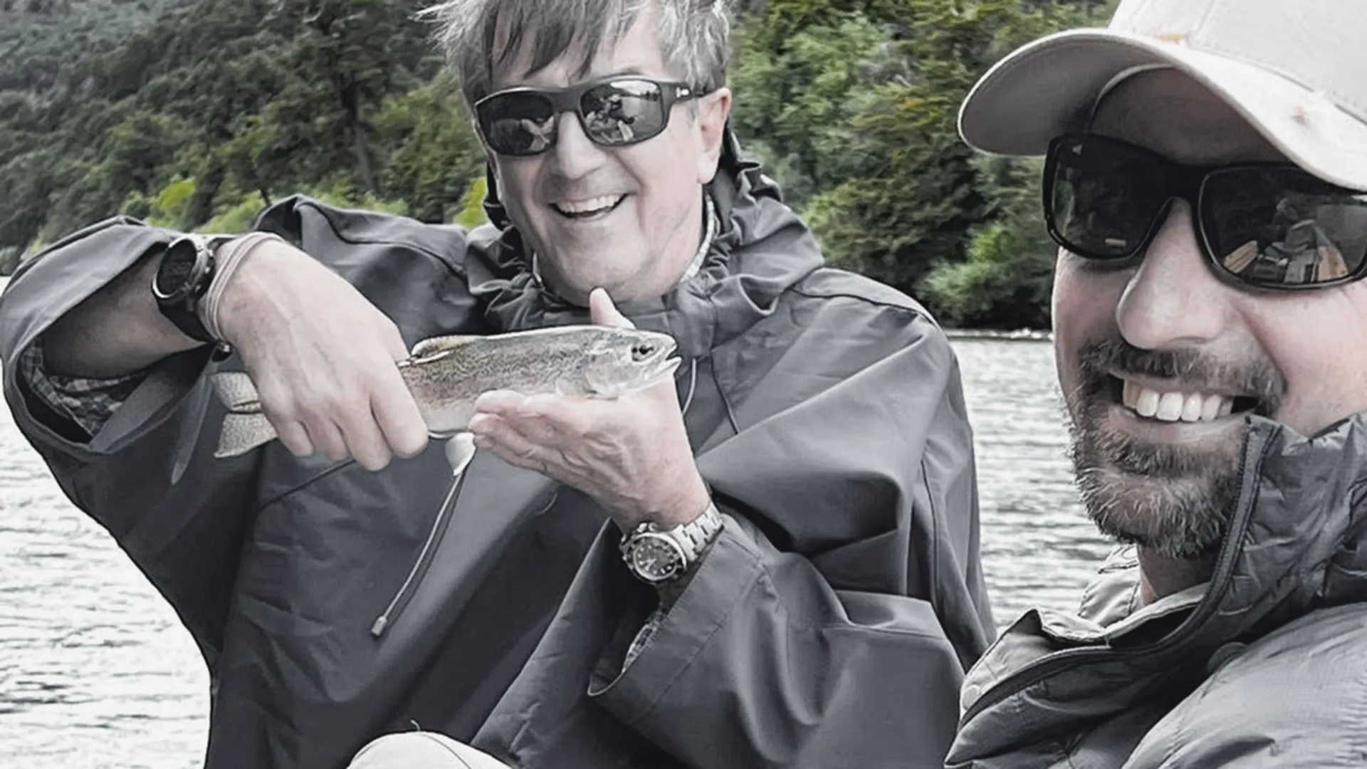 Two of the team with a fish to hand, on the river in the rain